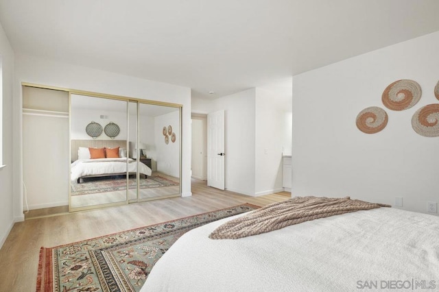 bedroom with light hardwood / wood-style floors and a closet