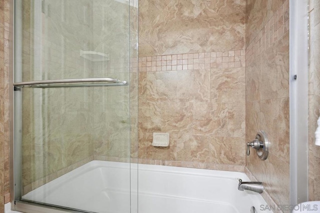 bathroom with bath / shower combo with glass door