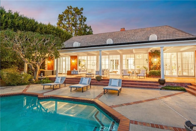 back house at dusk featuring a patio area