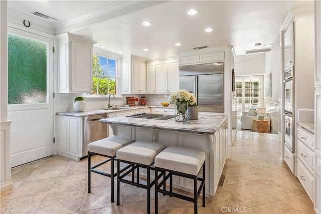 kitchen with stainless steel appliances, sink, a center island, white cabinetry, and a breakfast bar area