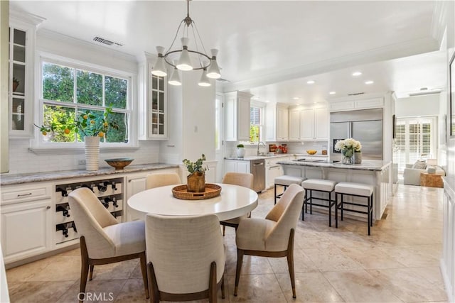 dining room featuring ornamental molding, sink, light tile patterned floors, and a chandelier