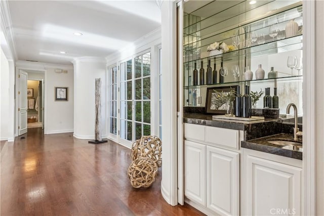 bar with white cabinets, dark hardwood / wood-style flooring, crown molding, and sink