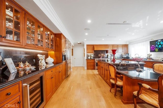 bar featuring backsplash, light hardwood / wood-style flooring, ornamental molding, stainless steel range, and beverage cooler