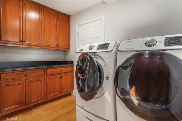 clothes washing area with cabinets, washer and clothes dryer, and light hardwood / wood-style floors