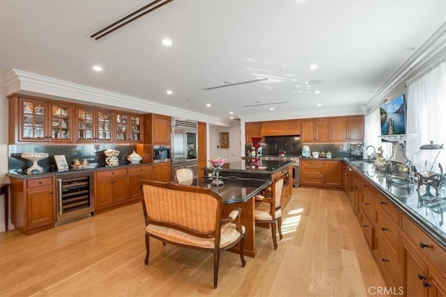 kitchen featuring a breakfast bar, stainless steel appliances, crown molding, light hardwood / wood-style floors, and wine cooler