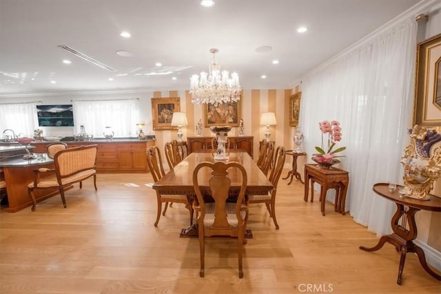 dining area featuring a chandelier, light wood-type flooring, and crown molding