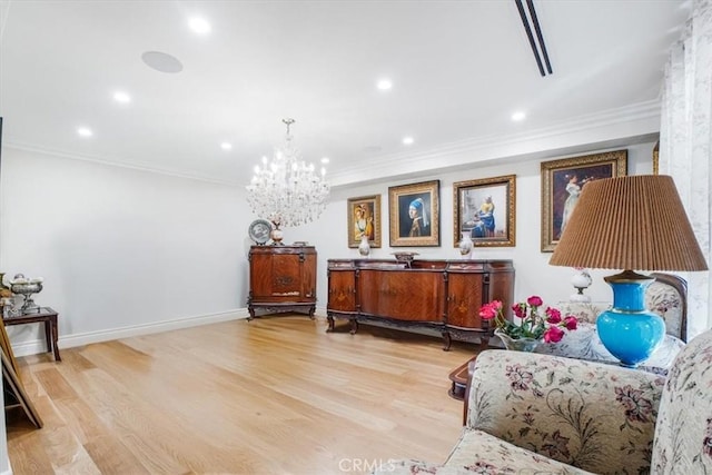 sitting room with a chandelier, light wood-type flooring, and crown molding