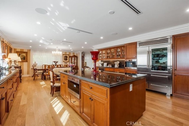 kitchen featuring a center island, a notable chandelier, light wood-type flooring, appliances with stainless steel finishes, and ornamental molding