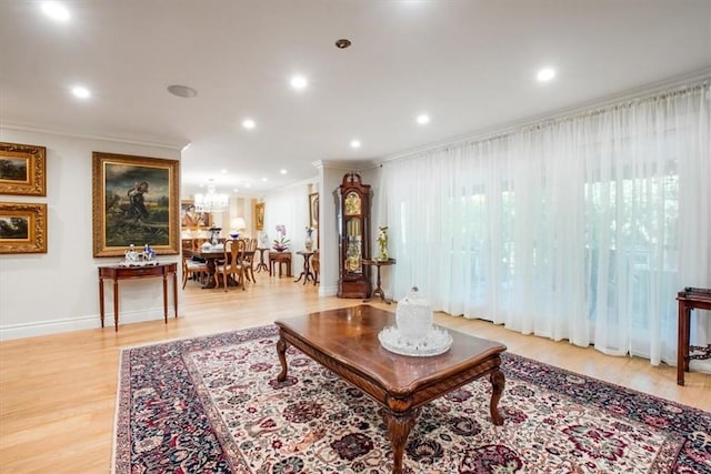 living room featuring a chandelier, crown molding, and light hardwood / wood-style floors