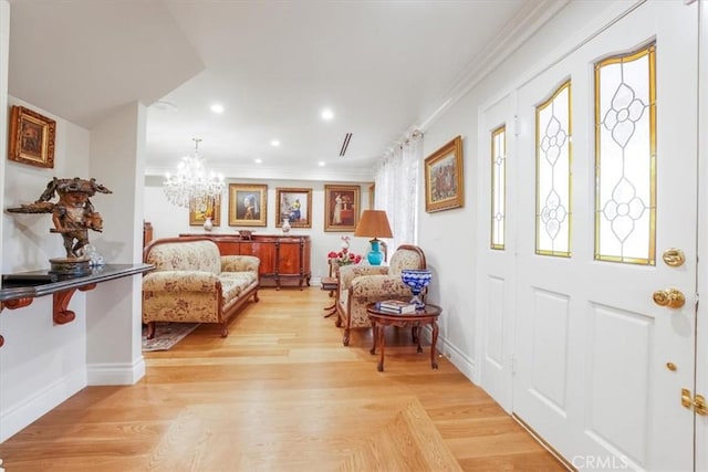 foyer featuring ornamental molding, light hardwood / wood-style floors, and an inviting chandelier