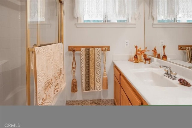 bathroom with a tile shower and vanity