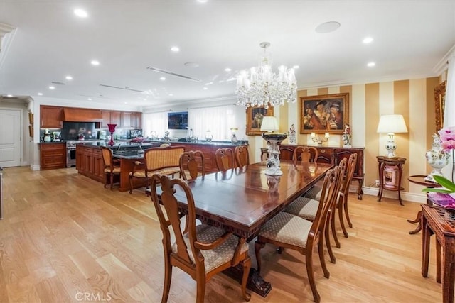 dining space with crown molding, a chandelier, and light wood-type flooring