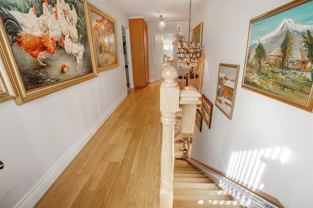 corridor featuring light hardwood / wood-style floors and an inviting chandelier