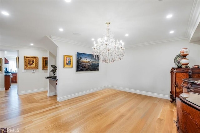 dining space with light wood-type flooring, ornamental molding, and an inviting chandelier