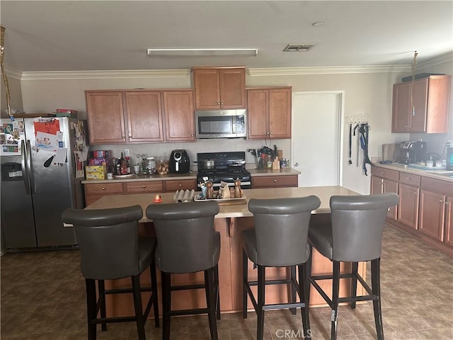 kitchen featuring a breakfast bar, a center island, stainless steel appliances, and ornamental molding