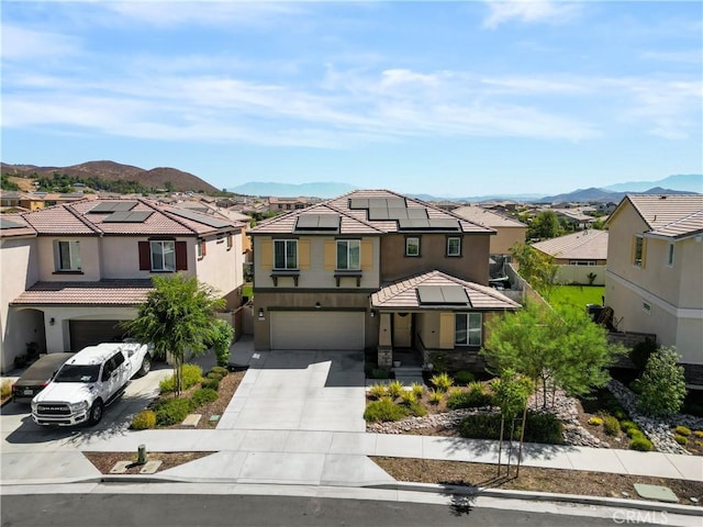 view of front of property with solar panels, a mountain view, and a garage