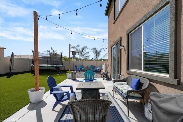 view of patio featuring an outdoor fire pit, grilling area, and a trampoline