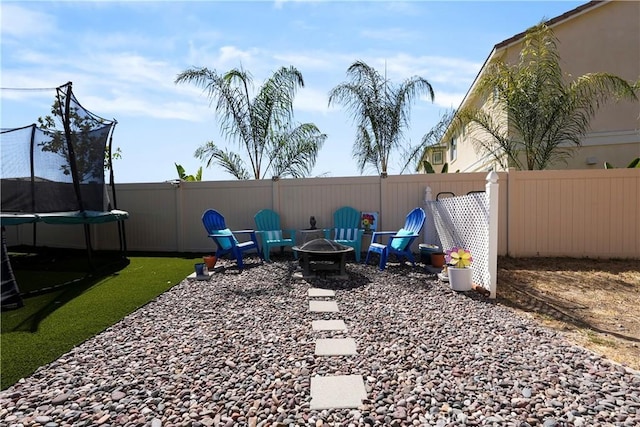 view of yard with a fire pit and a trampoline