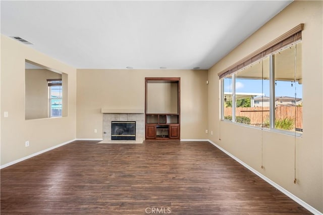 unfurnished living room with dark wood-type flooring and a tile fireplace