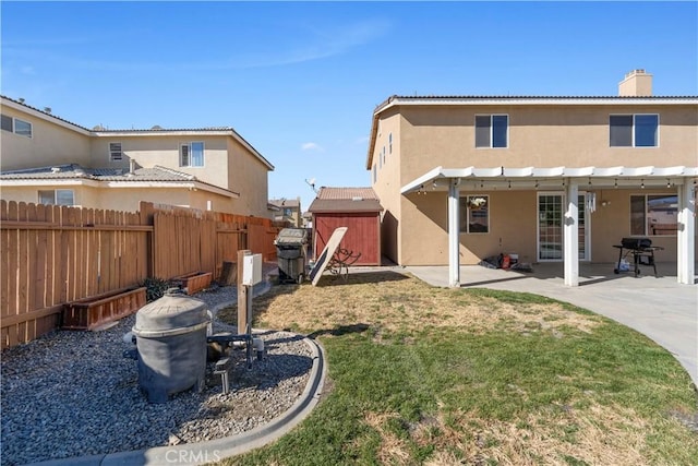 back of property featuring a storage shed, a yard, and a patio