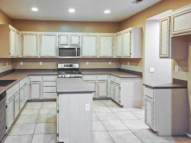 kitchen featuring stainless steel appliances, a kitchen island, sink, and light tile patterned floors