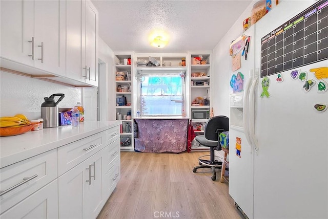 kitchen featuring light wood-type flooring, white cabinetry, a textured ceiling, black microwave, and fridge with ice dispenser