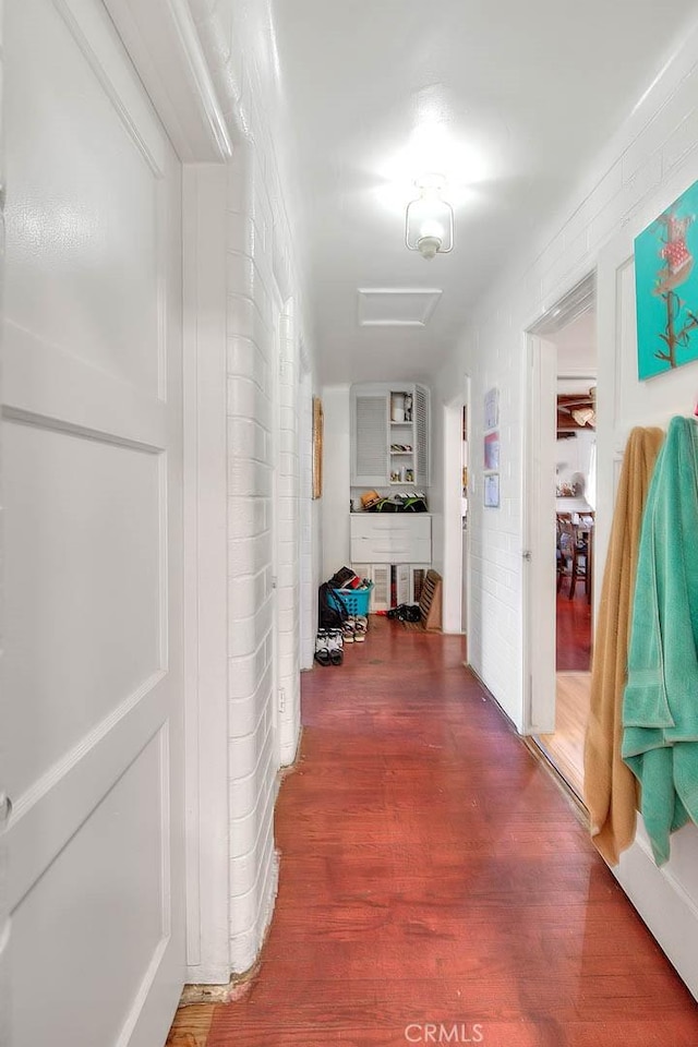 hallway with hardwood / wood-style floors and brick wall