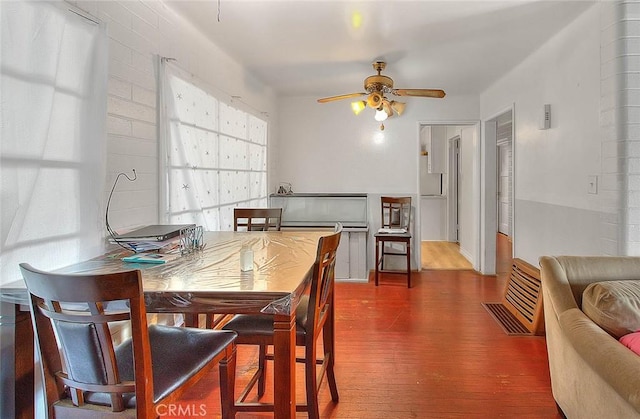 dining space with ceiling fan and wood-type flooring