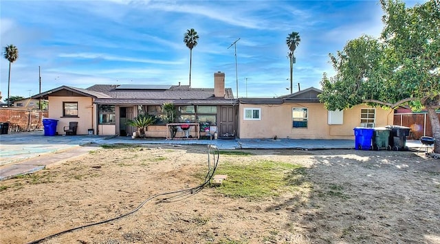 rear view of property with a patio and solar panels