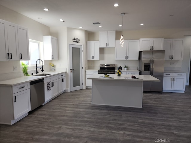 kitchen with a center island, white cabinetry, stainless steel appliances, hanging light fixtures, and dark hardwood / wood-style floors