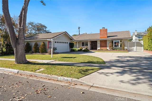 ranch-style home with a chimney, a gate, a garage, driveway, and a front lawn