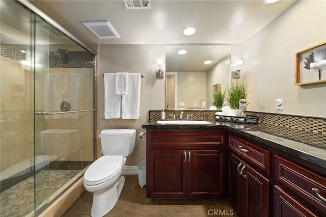 bathroom featuring backsplash, vanity, toilet, and a shower with door