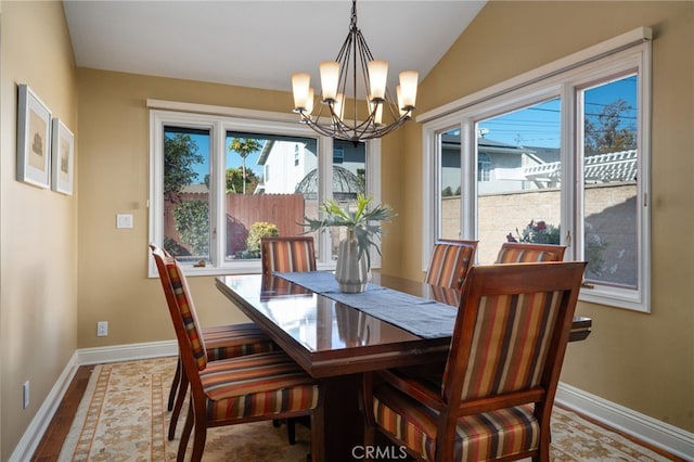 dining space with vaulted ceiling, a chandelier, and baseboards