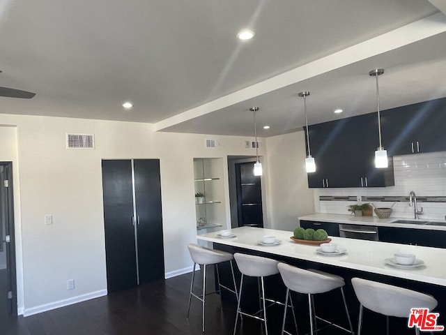 kitchen featuring pendant lighting, a kitchen breakfast bar, decorative backsplash, and sink