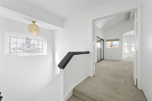 hall featuring lofted ceiling and light carpet