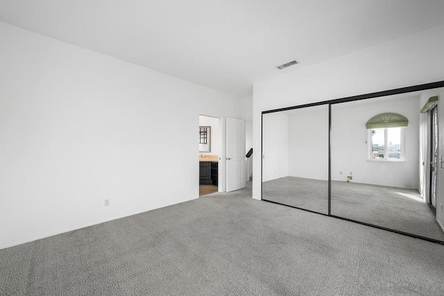 unfurnished bedroom with carpet, ensuite bath, and a closet