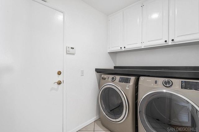 clothes washing area with light tile patterned flooring, cabinets, and independent washer and dryer