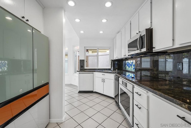 kitchen featuring white cabinetry, sink, stainless steel appliances, tasteful backsplash, and light tile patterned floors