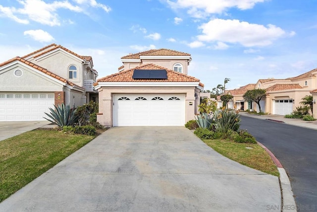 mediterranean / spanish-style house featuring solar panels and a garage