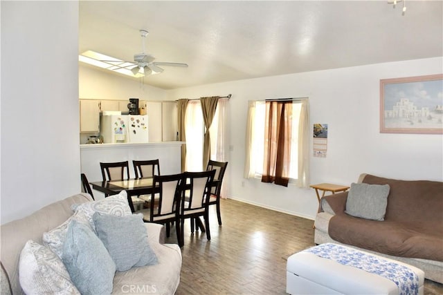 living room with ceiling fan, hardwood / wood-style floors, and vaulted ceiling