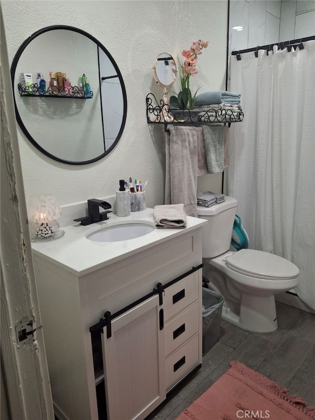 bathroom featuring curtained shower, toilet, vanity, and hardwood / wood-style flooring