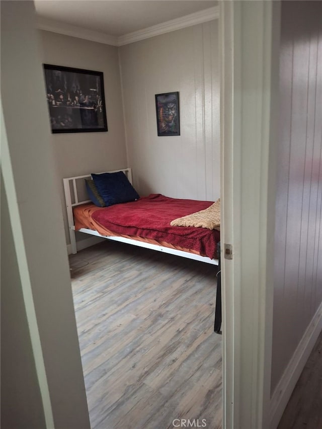 bedroom featuring hardwood / wood-style flooring, wood walls, and ornamental molding