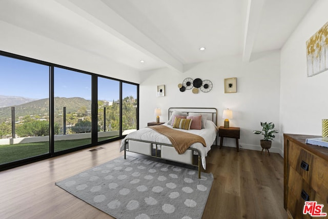 bedroom with dark hardwood / wood-style floors, beam ceiling, and a mountain view