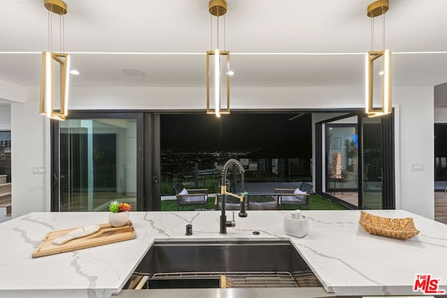 kitchen with sink, pendant lighting, and light stone counters