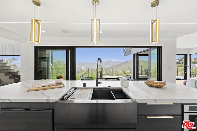 kitchen with light stone counters, a mountain view, and hanging light fixtures