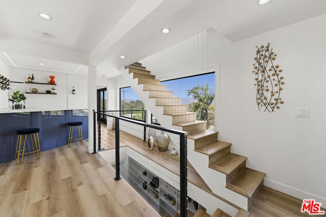 staircase with wood-type flooring and bar area