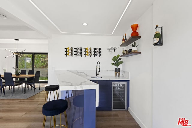 bar featuring sink, a tray ceiling, beverage cooler, and hardwood / wood-style floors