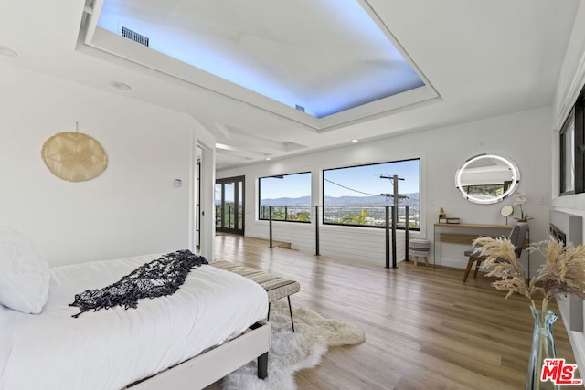 bedroom with a mountain view, hardwood / wood-style floors, and a tray ceiling