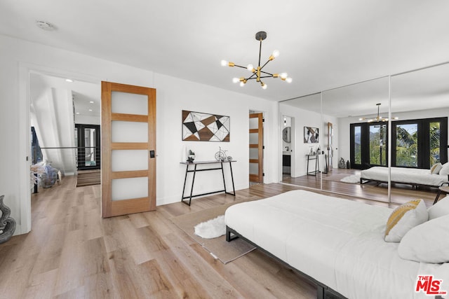 bedroom with french doors, an inviting chandelier, and light hardwood / wood-style flooring