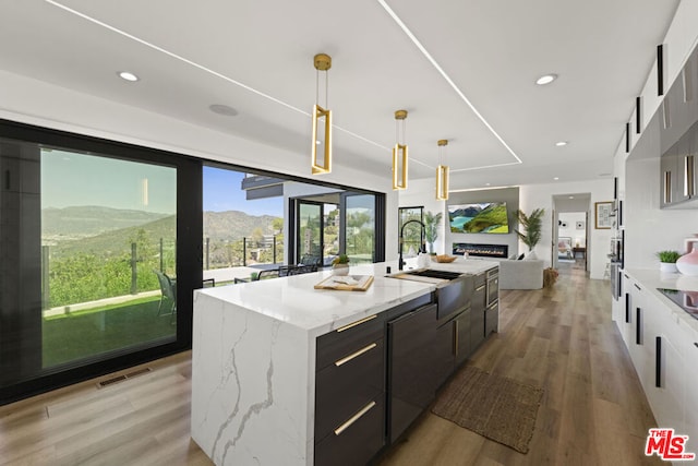 kitchen featuring sink, decorative light fixtures, light wood-type flooring, a mountain view, and a large island